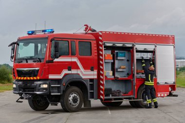 İtfaiyeci titizlikle modern bir itfaiye aracını tehlikeli durumlara müdahale ve boşaltma görevi için hazırlıyor. Yangına karşı güvenlik ve hazır olma azmini gösteriyor.