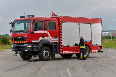 İtfaiyeci titizlikle modern bir itfaiye aracını tehlikeli durumlara müdahale ve boşaltma görevi için hazırlıyor. Yangına karşı güvenlik ve hazır olma azmini gösteriyor.