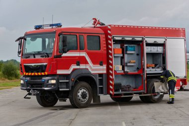 İtfaiyeci titizlikle modern bir itfaiye aracını tehlikeli durumlara müdahale ve boşaltma görevi için hazırlıyor. Yangına karşı güvenlik ve hazır olma azmini gösteriyor.
