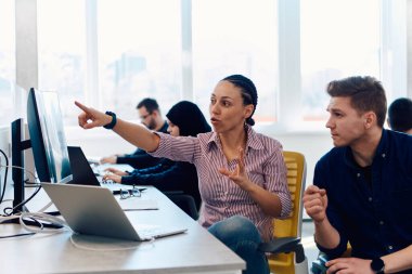 Ofiste yapılan beyin fırtınası sırasında çok kültürlü genç iş adamlarının ortak çalışma süreci. Resmi olarak giyinmiş çeşitli gençler tasarım projesinin geliştirilmesinde işbirliği yapıyor.