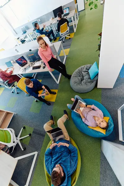 stock image In a modern startup office, a diverse group of young and capable businesspeople engage in lively discussions about various projects, showcasing teamwork, innovation, and entrepreneurial spirit. 