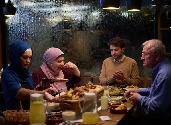 モダンで伝統的なヨーロッパのイスラムファミリーは ラマダン断食期間中に現代的なレストランでイタールのために集まり 文化的な調和と家族の団結を体現しています — ストック写真