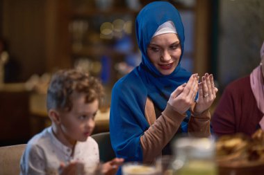 Modern bir restoran ortamında, Avrupalı bir İslami aile iftar için Ramazan ayında bir araya gelir, yemekten önce dua eder, gelenek ve çağdaş uygulamaları bir kutlama için birleştirir.