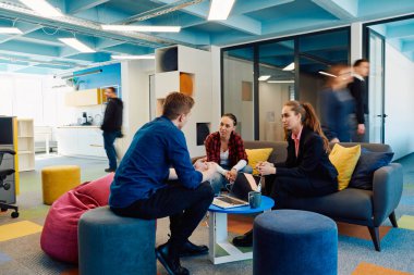 Çok ırklı bir girişim ekibi modern, açık alan çalışma ofisinde toplanıyor. Beyin fırtınası, dizüstü bilgisayarda çalışmak. Hareket bulanıklığı içinde dolaşan bir grup iş arkadaşı.