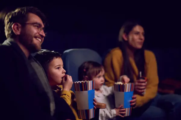 近代的な家族は映画館で一緒に質の高い時間を楽しみ 子供と一緒に映画を見ながらポップコーンにふける — ストック写真