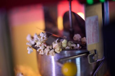 A close-up shot captures the mesmerizing process of making cinema popcorn, with kernels popping and releasing an irresistible aroma, promising a delightful snack for moviegoers. clipart