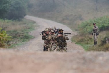 Disiplinli ve özel bir askeri birlik, kamuflajlı, stratejik devriye gezen ve yüksek bahisli bir ortamda kontrolü elinde tutan, hassasiyetlerini, birliklerini ve hazırlıklarını gösteren