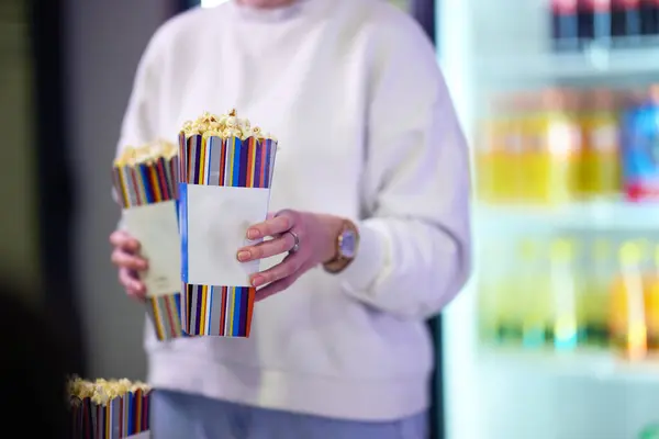 stock image A vendor stands outside the cinema, holding freshly popped popcorn to sell to moviegoers before they enter the theater.