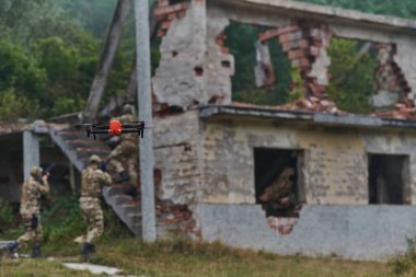Elit askeri birim, son teknolojiyle donatılmış insansız hava aracı dahil, stratejik olarak ormanlık alanda geziniyor ve araştırıyor, hassasiyetlerini, iş birliklerini ve uzmanlıklarını gösteriyor.