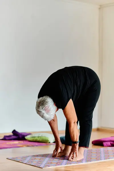 在阳光普照的空间里 一位老妇人优雅地练习恢复瑜伽的活力 专注于脖子 背和腿的伸展 体现了宁静和幸福 — 图库照片