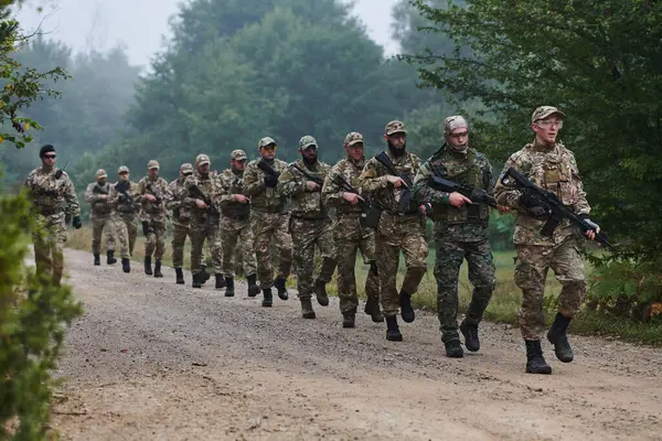 stock image An elite military unit, led by a major, confidently parades through dense forest, showcasing precision, discipline, and readiness for high-risk operations. 