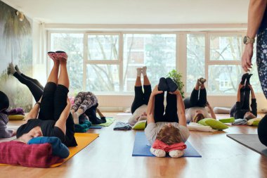 Bir grup son sınıf öğrencisi, güneş alan bir alanda eğitmenin rehberliğinde boyun, sırt ve bacak esnetme gibi çeşitli yoga egzersizleri yaparak refahı ve uyumu sağlıyorlar.. 