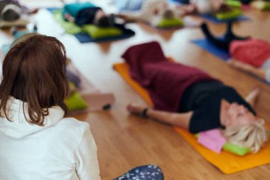 Bir grup son sınıf öğrencisi, güneş alan bir alanda eğitmenin rehberliğinde boyun, sırt ve bacak esnetme gibi çeşitli yoga egzersizleri yaparak refahı ve uyumu sağlıyorlar.. 