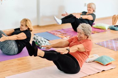 Bir grup son sınıf öğrencisi, güneş alan bir alanda eğitmenin rehberliğinde boyun, sırt ve bacak esnetme gibi çeşitli yoga egzersizleri yaparak refahı ve uyumu sağlıyorlar.. 