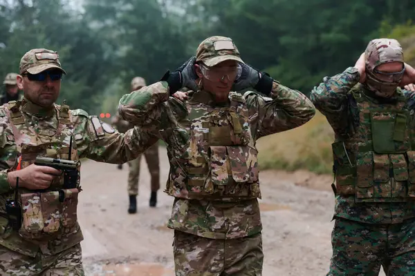 stock image A group of elite soldiers leads captives through a military camp, showcasing a tense atmosphere of detention and security operations. 