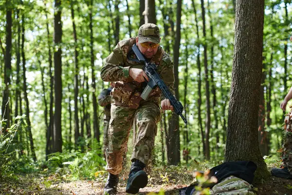 stock image An elite soldier, camouflaged and stealthily navigating through dangerous woodland terrain, executes a covert mission in a secluded forest area. 