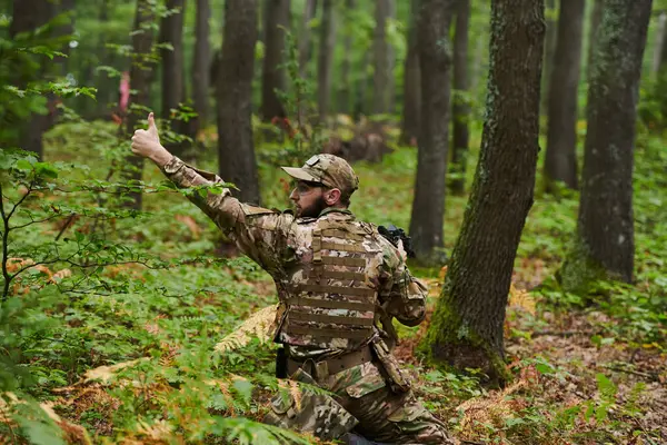 stock image An elite soldier, camouflaged and stealthily navigating through dangerous woodland terrain, executes a covert mission in a secluded forest area. 