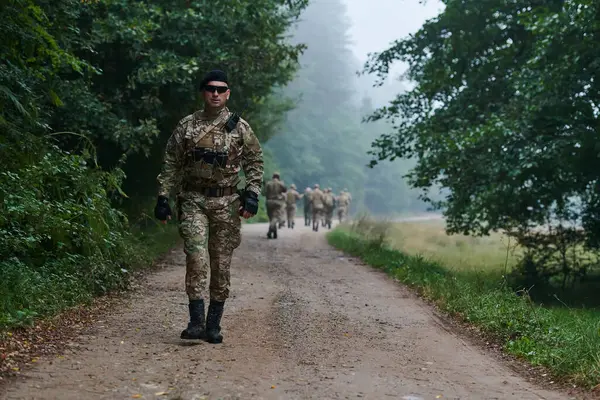 stock image A group of elite soldiers leads captives through a military camp, showcasing a tense atmosphere of detention and security operations. 