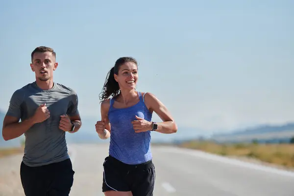 A couple runs through a sun-dappled road, their bodies strong and healthy, their love for each other and the outdoors evident in every stride.
