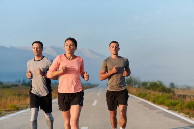 Bir grup arkadaş, sporcu ve koşucu sabahın erken saatlerinde güneşin doğuşuyla enerji dolu ve doğanın sakin güzelliğiyle çevrelenmiş bir şekilde puslu şafakta koşarken kucaklaşıyorlar.. 