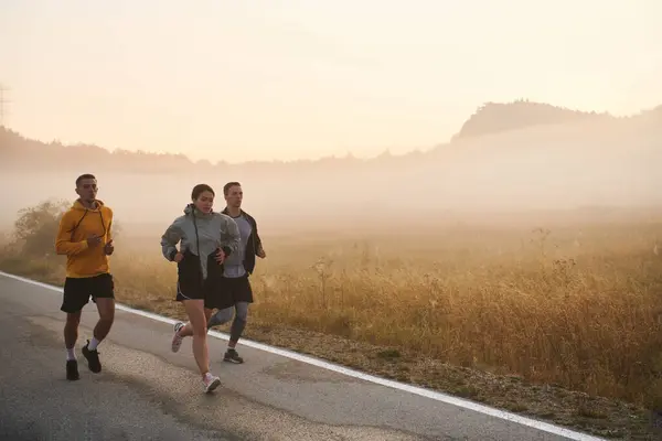 一群朋友 运动员和慢跑者在黎明时分拥抱在一起 他们在朦胧的黎明中奔跑 在升起的太阳的激励下 在宁静的自然美的包围下 奔跑着 — 图库照片