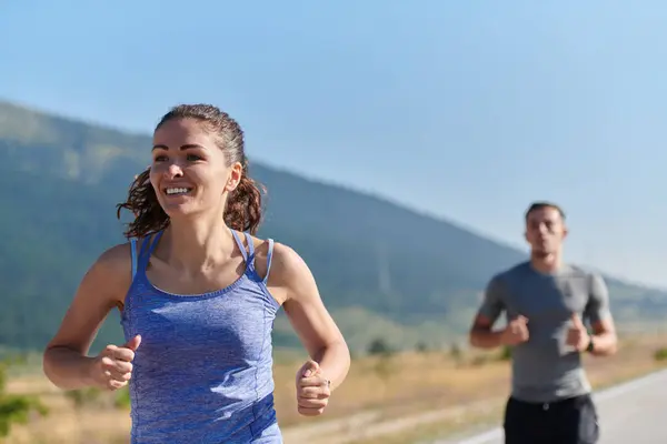 A couple runs through a sun-dappled road, their bodies strong and healthy, their love for each other and the outdoors evident in every stride.