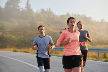 Bir grup arkadaş, sporcu ve koşucu sabahın erken saatlerinde güneşin doğuşuyla enerji dolu ve doğanın sakin güzelliğiyle çevrelenmiş bir şekilde puslu şafakta koşarken kucaklaşıyorlar.. 