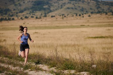 Atletik bir kadın sağlıklı bir yaşam tarzında özgürlük ve neşe bulur. Gün doğumunda güzel bir patikada koşar.. 