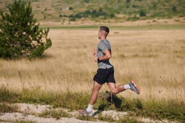 Atletik bir adam koşarken kararlılığını sergiler, sağlıklı bir yaşam tarzına ve yaklaşan maraton yarışmasına hazırlanmaya bağlıdır.