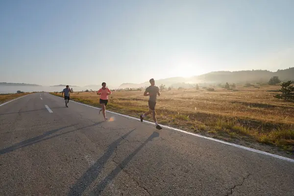 一群朋友 运动员和慢跑者在黎明时分拥抱在一起 他们在朦胧的黎明中奔跑 在升起的太阳的激励下 在宁静的自然美的包围下 奔跑着 — 图库照片