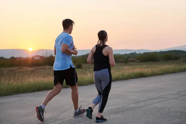 一对充满活力的夫妇在户外奔跑 体现了运动和浪漫的本质 他们自信的步伐反映了对健身的共同承诺和对未来马拉松赛的准备 — 图库照片