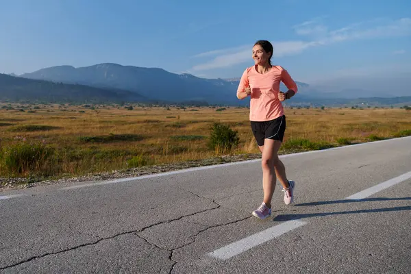 stock image A resolute and motivated athlete running confidently into the sunrise, epitomizing determination and empowerment in her early morning run. 