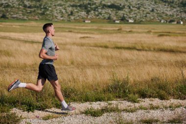 Atletik bir adam koşarken kararlılığını sergiler, sağlıklı bir yaşam tarzına ve yaklaşan maraton yarışmasına hazırlanmaya bağlıdır.