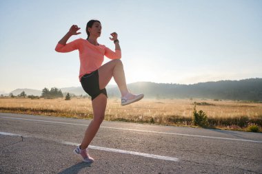  Kararlı bir atletik kadın koşudan sonra esneme hareketleri yapar, spor yolculuğuna kendini adamaya ve vücudunun esnekliğini ve esnekliğini arttırmaya çalışır.