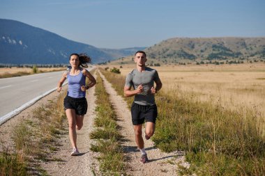 Bir çift güneş lekeli bir yolda koşar, vücutları güçlü ve sağlıklıdır, birbirlerine olan sevgileri ve her adımda aşikardır.. 