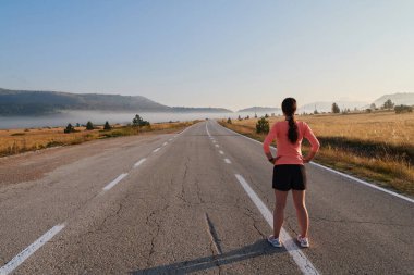  Kararlı bir atletik kadın koşudan sonra esneme hareketleri yapar, spor yolculuğuna kendini adamaya ve vücudunun esnekliğini ve esnekliğini arttırmaya çalışır.