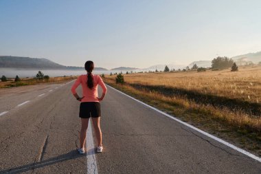  Kararlı bir atletik kadın koşudan sonra esneme hareketleri yapar, spor yolculuğuna kendini adamaya ve vücudunun esnekliğini ve esnekliğini arttırmaya çalışır.