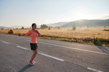  Kararlı bir atletik kadın koşudan sonra esneme hareketleri yapar, spor yolculuğuna kendini adamaya ve vücudunun esnekliğini ve esnekliğini arttırmaya çalışır.