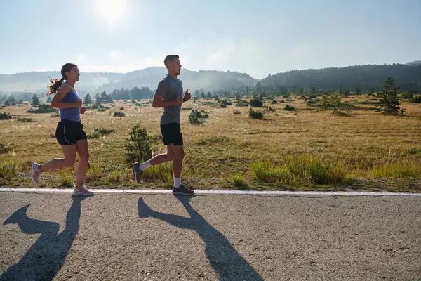一对夫妇在一条阳光普照的路上奔跑 他们的身体强壮健康 他们彼此相爱 每走一步 户外都是显而易见的 — 图库照片
