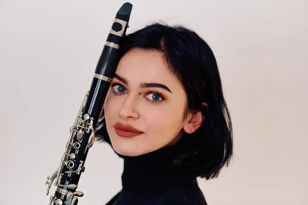 一位才华横溢的黑发音乐家优雅地拿起单簧管 在原始的白色背景下演奏 展现了她的艺术才华 — 图库照片