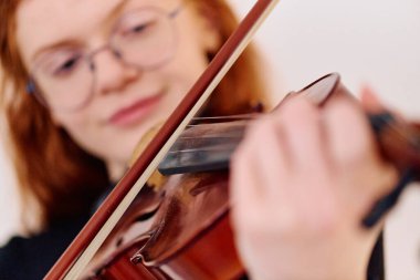 Çarpıcı kızıl saçlı bir müzisyen kemanıyla poz verirken zarafet ve müzikal hünerlerini sergiliyor..