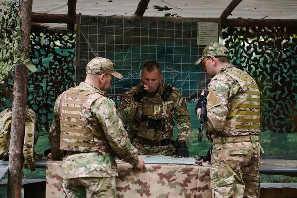 高度に訓練された軍事部隊は ブリーフィングセッション中に軍事地図を研究しながら戦術ミッションを戦略化し 組織します — ストック写真