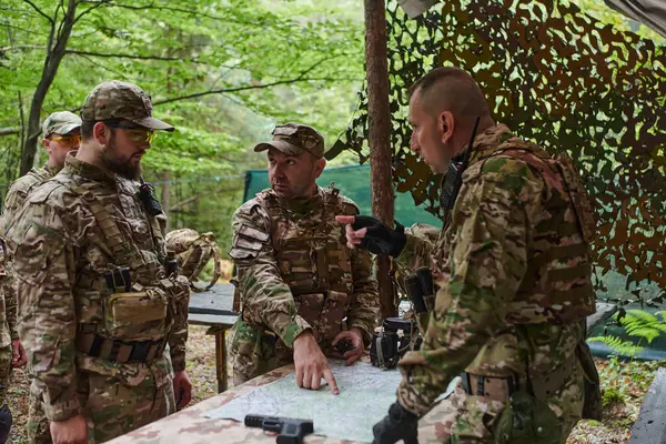 高度に訓練された軍事部隊は ブリーフィングセッション中に軍事地図を研究しながら戦術ミッションを戦略化し 組織します — ストック写真