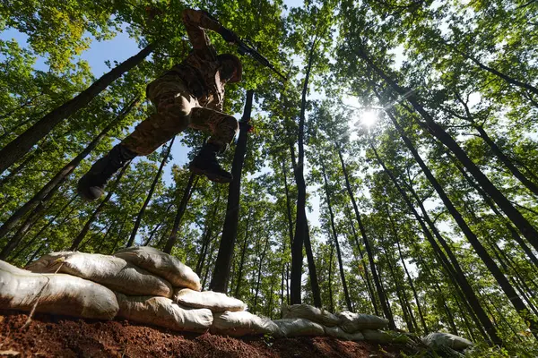 一名精锐的士兵在险峻的森林中巧妙地清除了军事障碍 在专门训练中展示了战术技巧和灵活性 — 图库照片