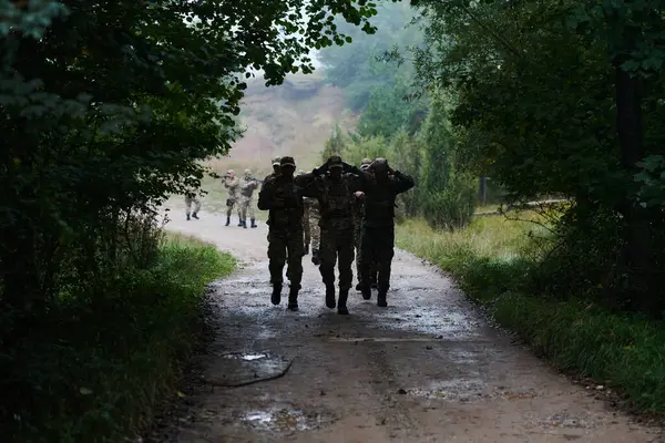 Grupa Elitarnych Żołnierzy Prowadzi Jeńców Przez Obóz Wojskowy Pokazując Napiętą — Zdjęcie stockowe