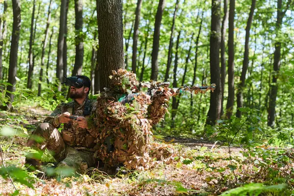 一名熟练狙击手和一名手持Vr护目镜操作无人机的士兵在森林中策划和观察军事行动 — 图库照片