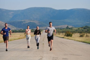 Bir grup arkadaş, güneşli bir günde dışarıda koşuşturarak sağlıklı bir yaşam tarzını sürdürüyor. Spor ve doğanın enerji verici etkilerinden keyif alıyorlar.. 