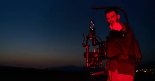 Stock image A skilled videographer captures the intensity of athletes running, illuminated by vibrant red lights, encapsulating the energy and determination of their nighttime training session.