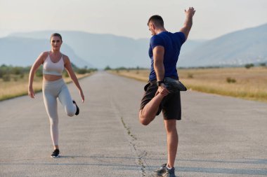 Kararlı bir grup sporcu koşularından önce kolektif bir esneme oturumuna katılıyor, takım çalışmasını teşvik ediyor ve fitness hedeflerini gerçekleştirmek için hazırlık yapıyorlar..