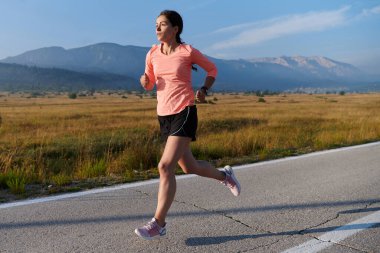 Kararlı ve motive olmuş bir sporcu gün doğumuna güvenle koşuyor, sabah koşusunda kararlılığını ve gücünü özetliyor..
